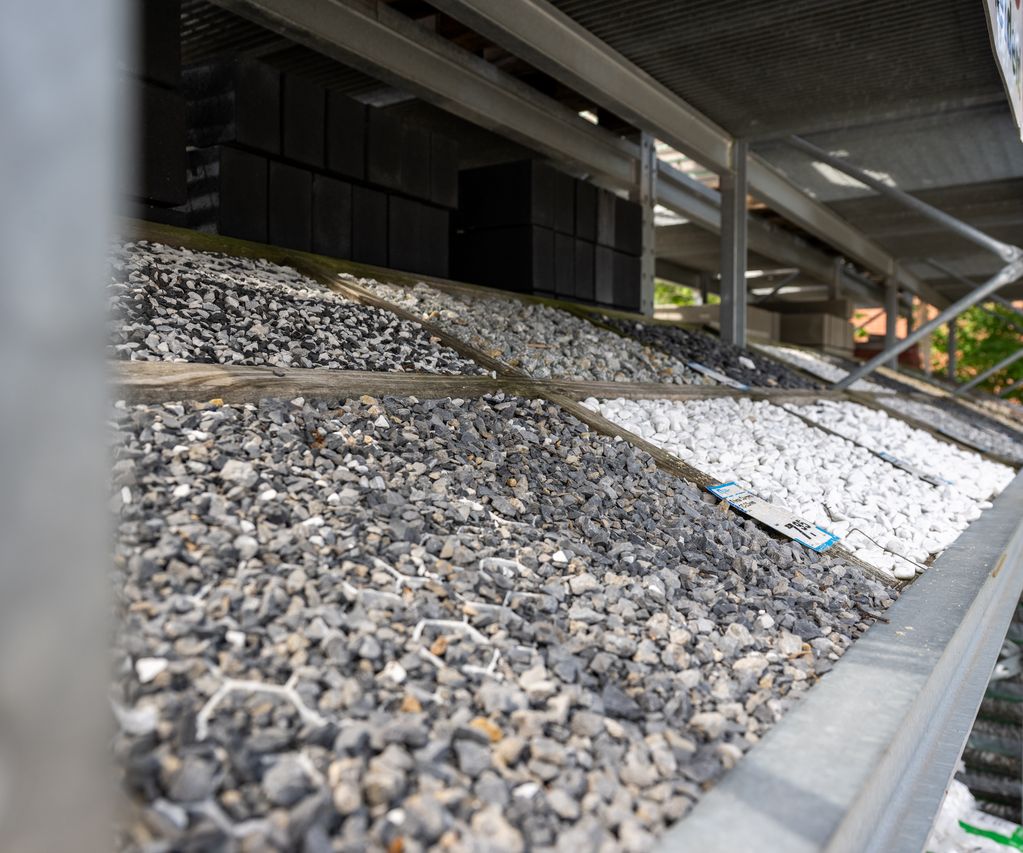 Verschiedene Schüttgüter wie grauer und weißer Zierkies in schrägen Lagerboxen.