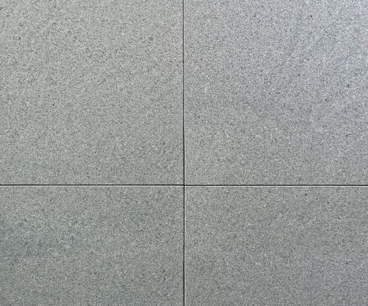 Graue Terrassenplatten mit fein strukturierter Oberfläche und dunklen Fugen in der Nahaufnahme