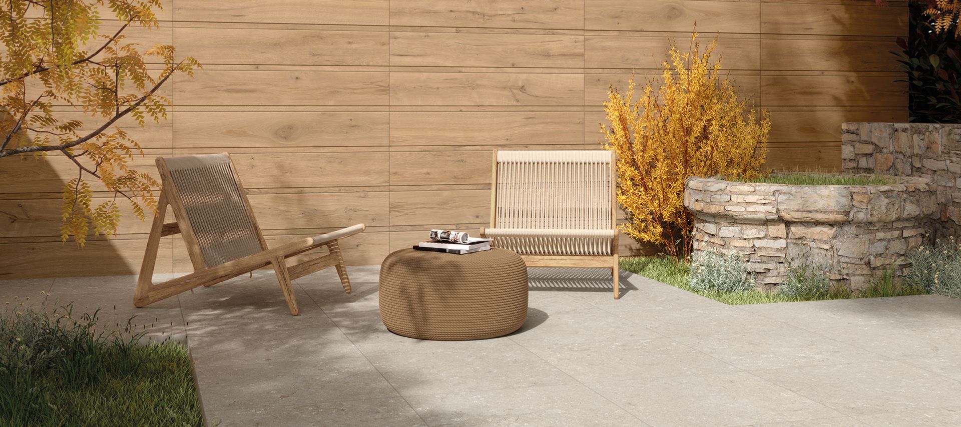 Moderner Terrassenbereich mit großformatigen hellgrauen Keramikterrassenplatten, Sitzmöbeln und bepflanztem Natursteinbeet.
