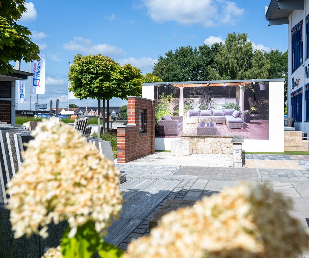 Baustoff-Ausstellung bei bauXpert Wilkens mit Pflasterflächen, Mauersteinen und Musterplatten im Außenbereich