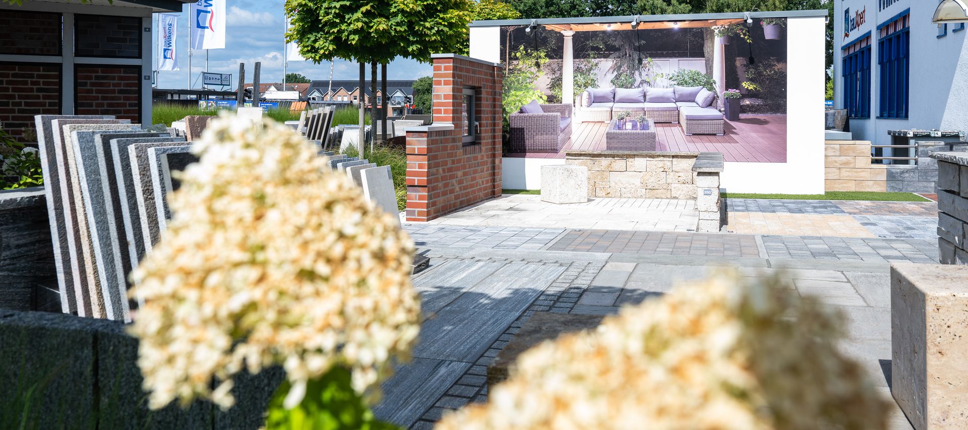 Baustoff-Ausstellung bei bauXpert Wilkens mit Pflasterflächen, Mauersteinen und Musterplatten im Außenbereich