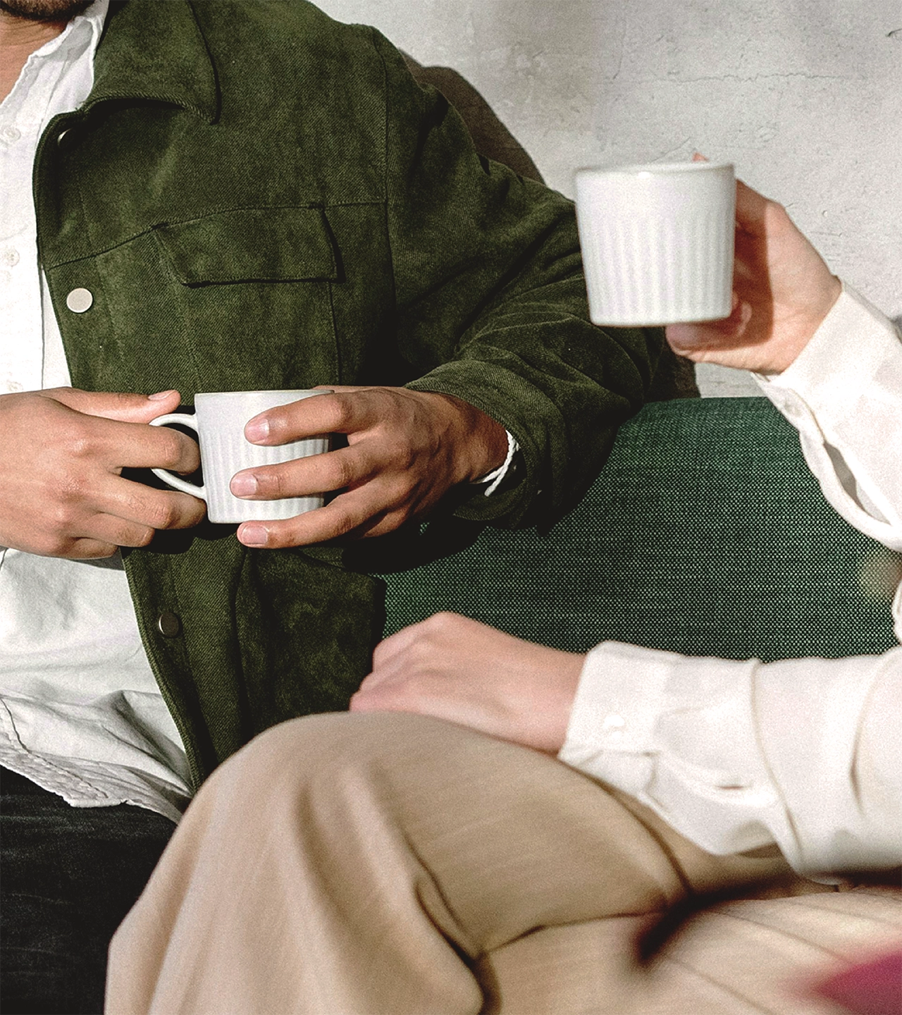 Two people holding coffee cups, showing hands and partial view of clothing