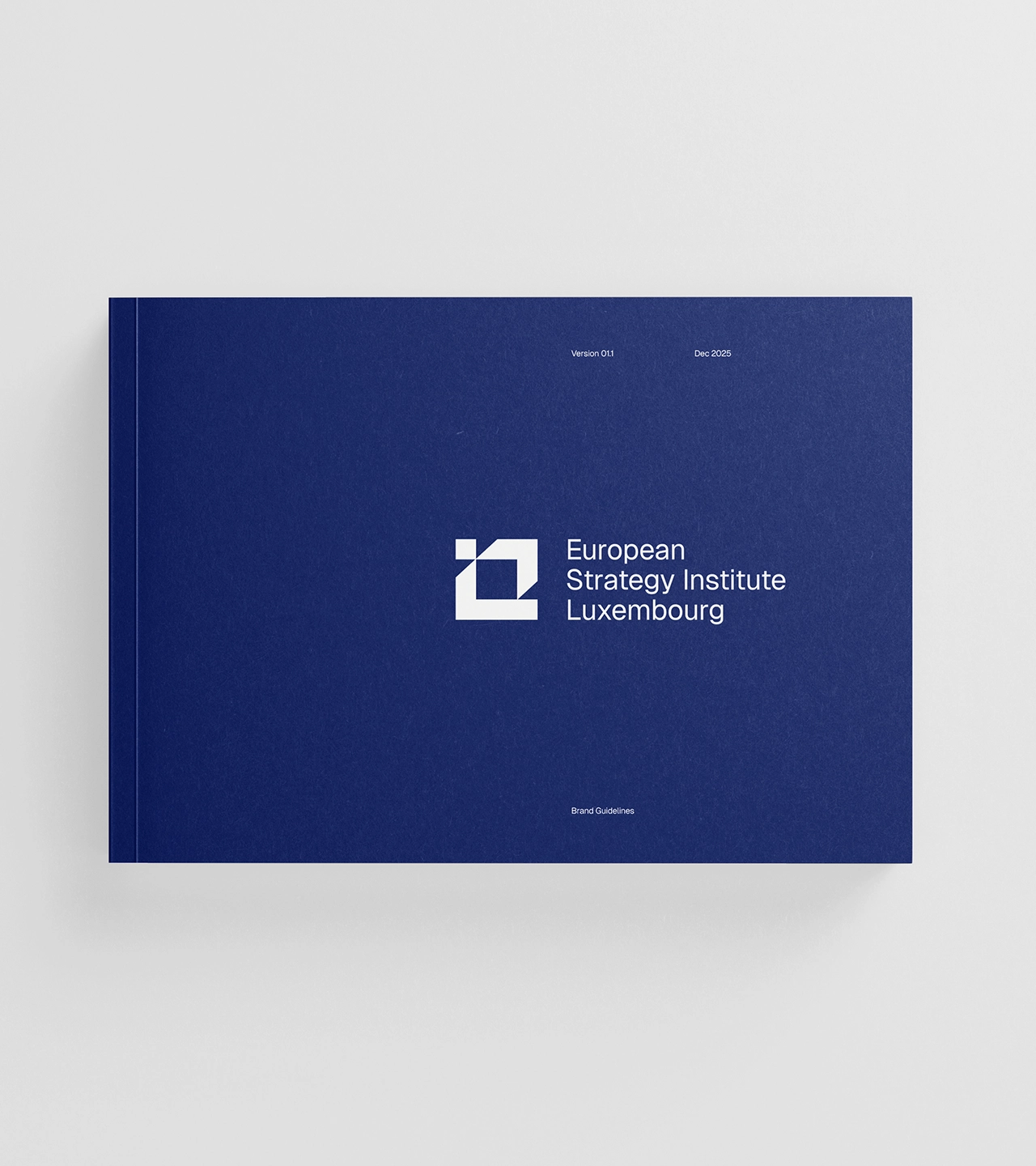 ESILUX brand guidelines hardcover book mockup — navy blue landscape-format cover featuring white geometric logo and European Strategy Institute Luxembourg wordmark