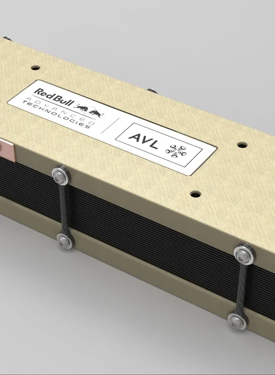 A rectangular metal enclosure with a beige top and black sides, featuring logos for Red Bull, AVL, and World Engines, secured with bolts.
