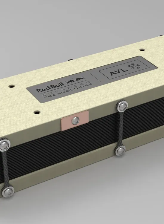 A rectangular, beige and black electronic device with metal bolts and labeled "Red Bull" and "AVL" on a metallic plaque on its top surface.