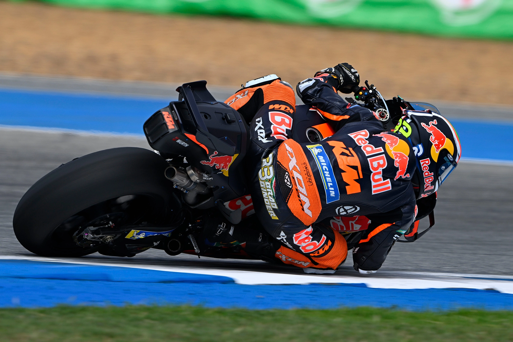 Brad Binder leans into a sharp turn on a race track, showcasing speed and precision.