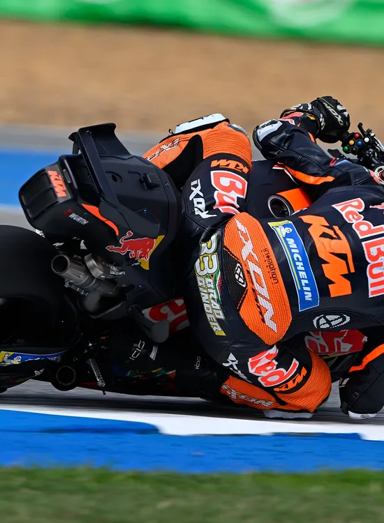 Brad Binder leans into a sharp turn on a race track, showcasing speed and precision.