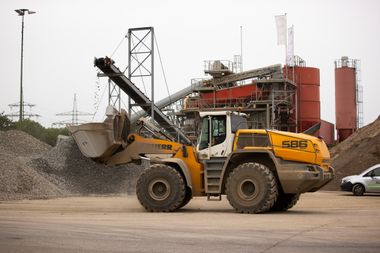 Ein Bagger verlädt Rohstoffe auf einer Deponie.