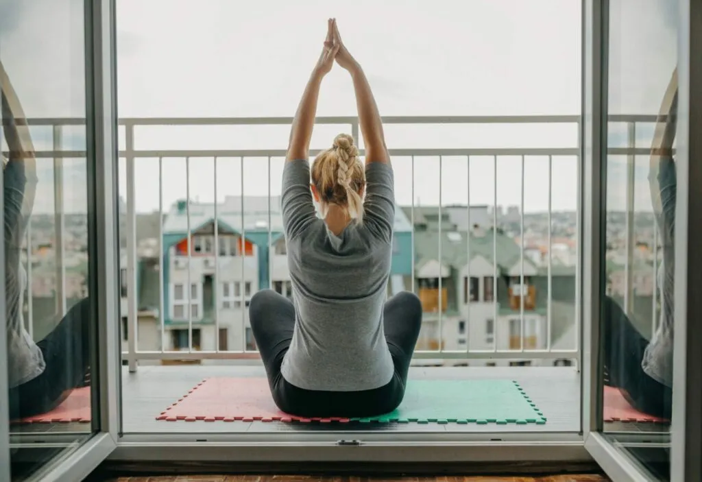 donna fa esercizi posturali sul balcone a casa