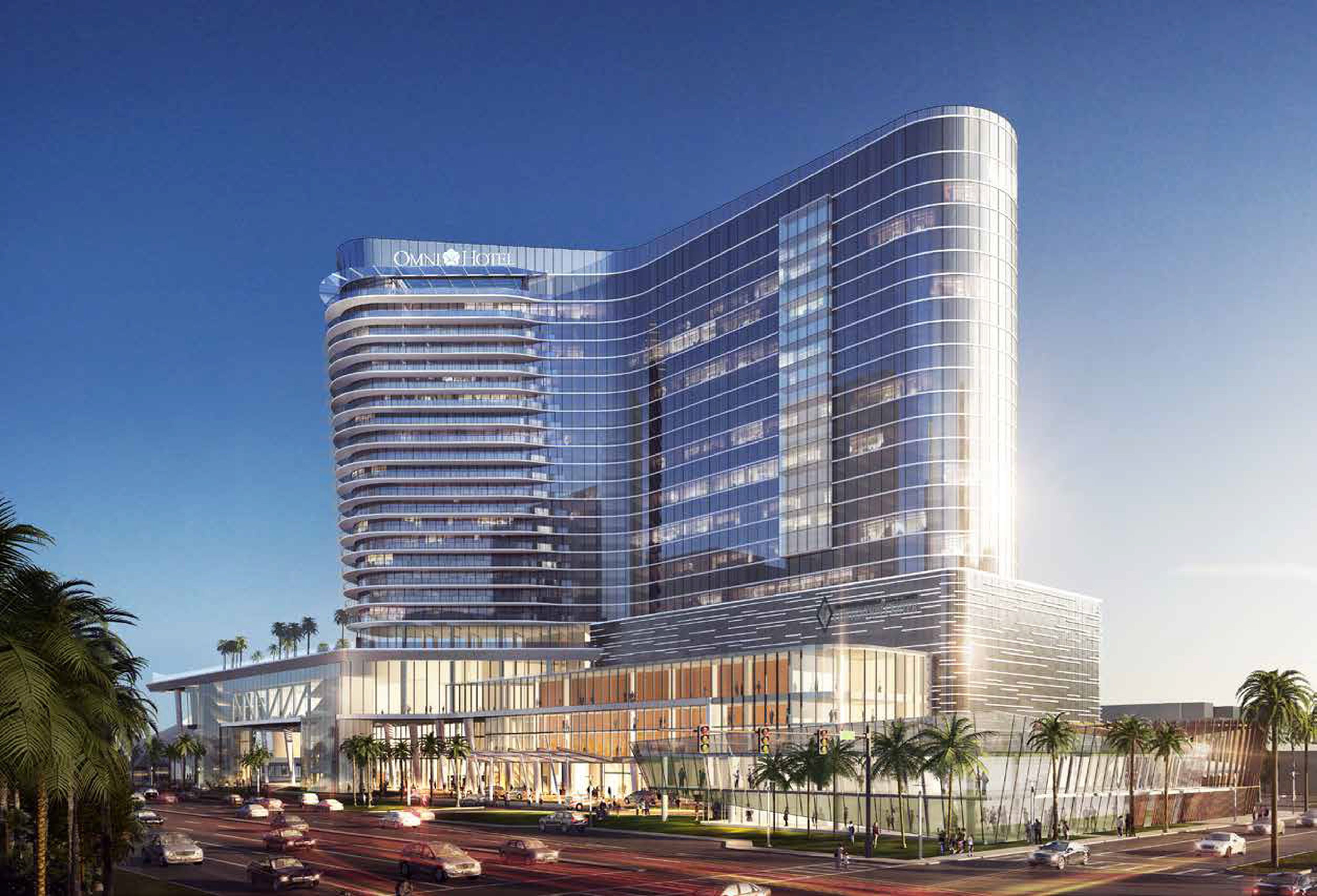 Modern multi-story tower atop large, 4-story podium shown at dusk. Tower has an L-shaped design with curved edges and blueish glass facade reflecting sunlight. Palm trees line the street below, with cars passing by.