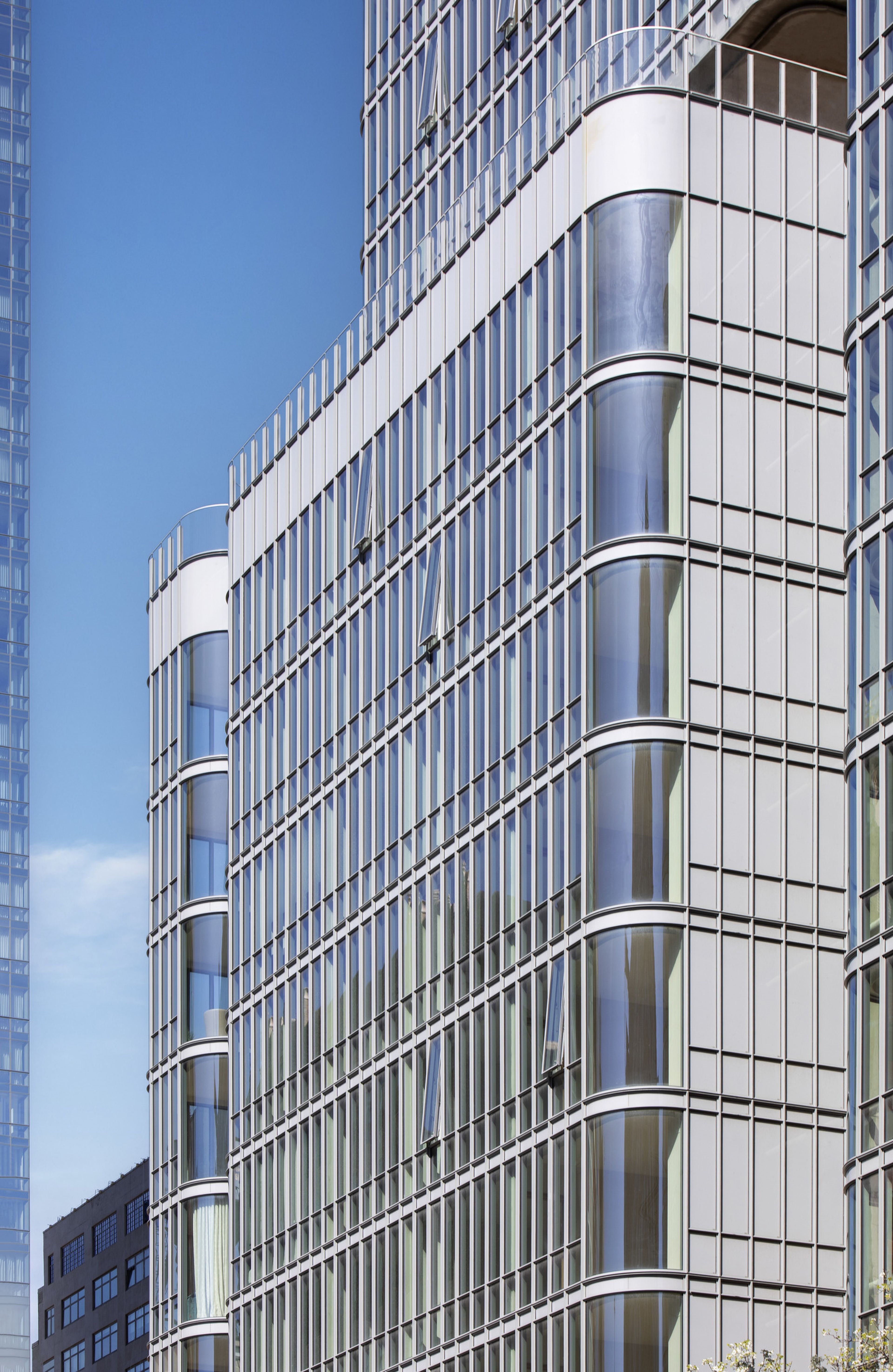 Modern glass building against a clear blue sky, featuring reflective windows and rounded corners.