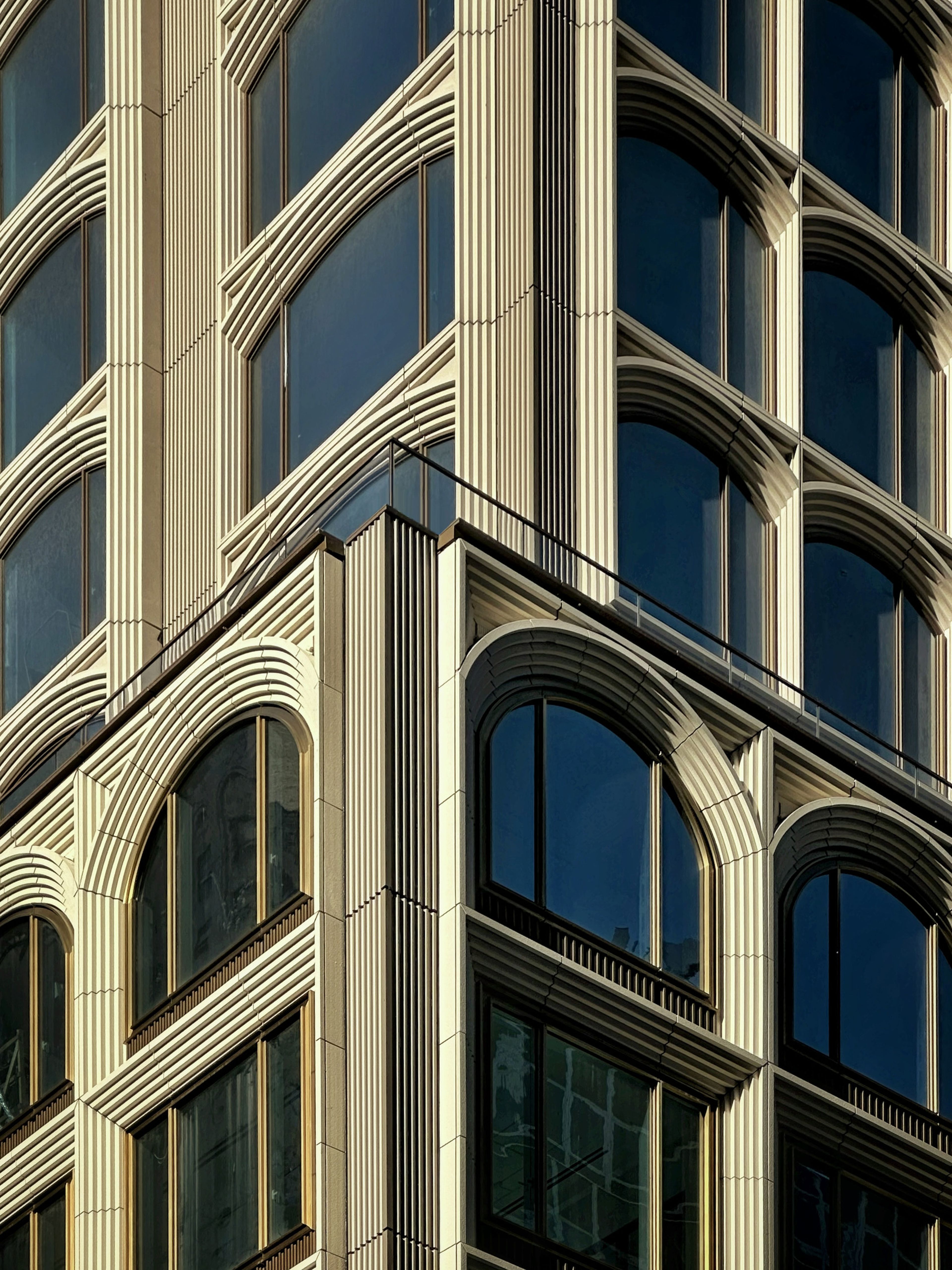 Close-up of a modern building facade with ornate vertical columns and large arched windows, featuring a detailed geometric architectural design