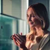 Frau lächelt mit einer Tasse in der Hand