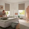 Frau sitzt auf einem Bett mit Plissees im Hintergrund