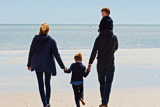 Famille marchant le long de l'océan à Deauville pendant leur séjour à l'hôtel Le normandy.