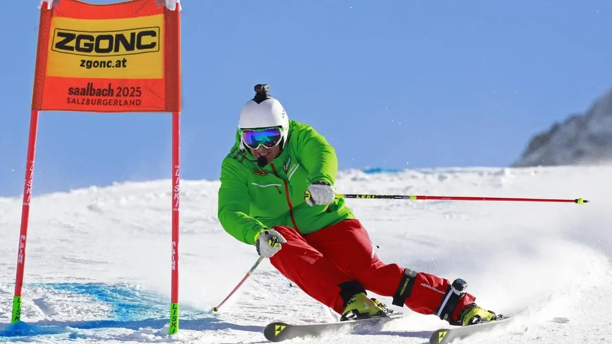 Skifahrer in grüner Jacke und roter Hose umfährt eine Torstange bei einem Rennen in Saalbach 2025, Salzburgerland.