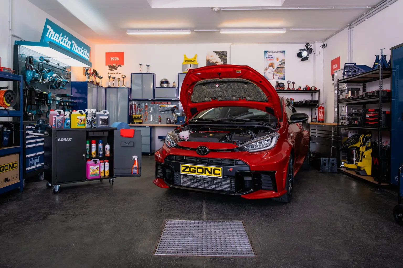 Roter Toyota GR Yaris mit geöffneter Motorhaube in der ZGONC-Werkstatt, umgeben von Werkzeug, Makita- und Sonax-Produkten.