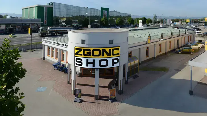 Außenansicht des Zgonc Shops, ein Fachmarkt für Werkzeuge, Maschinen und Baubedarf, mit markanter runder Fassade.