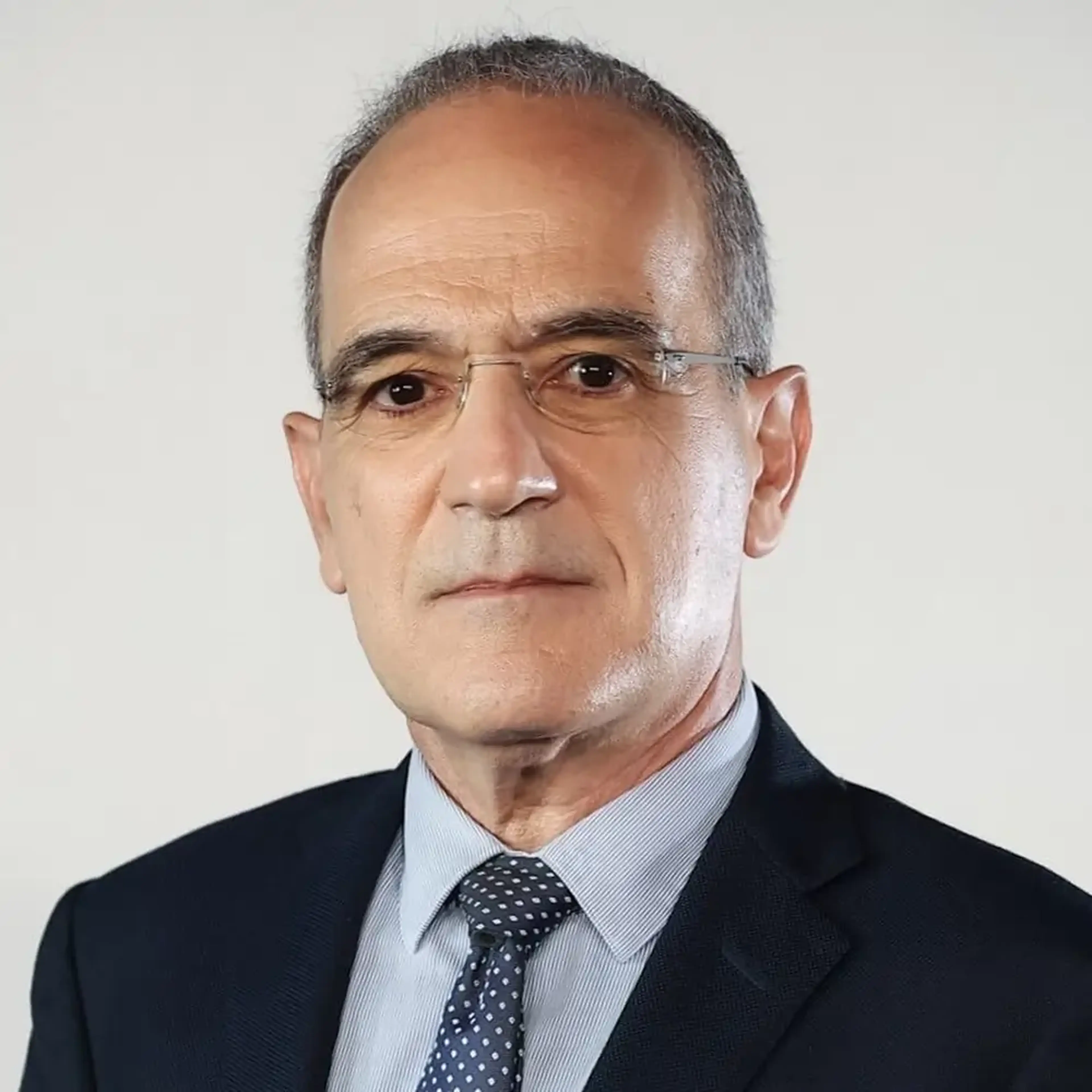 Professional headshot of Dr. Georgios Stergiou, middle-aged man with glasses wearing dark business suit and polka dot tie against white background