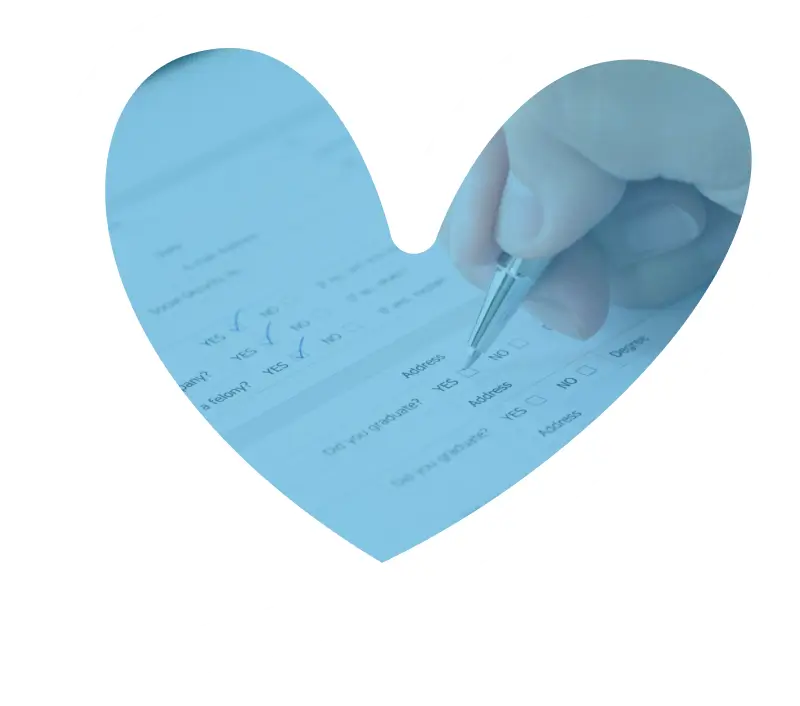 Heart-shaped image showing hand holding pen over medical documents, symbolizing compassionate healthcare and attention to patient details