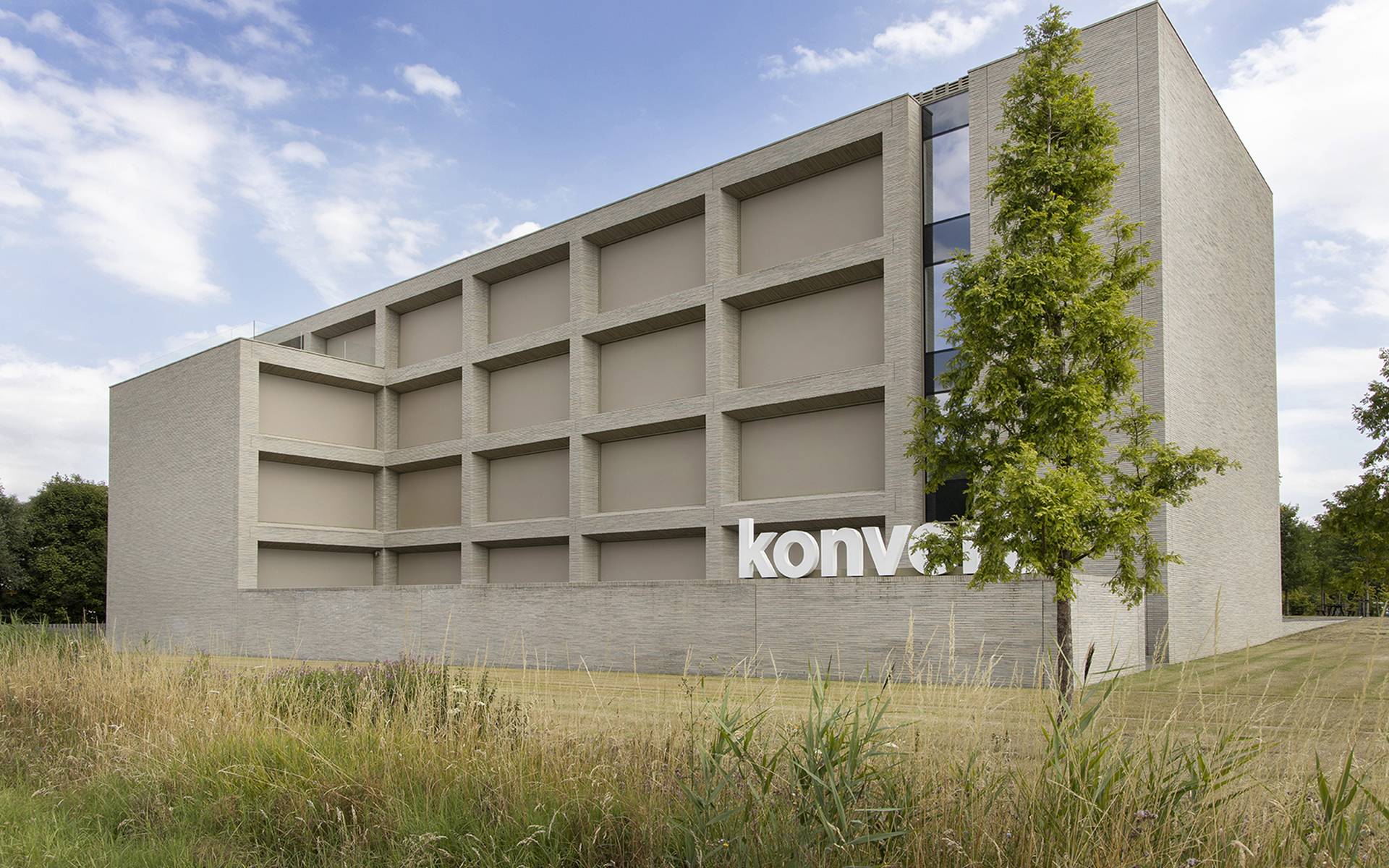 Vista esterna dell’edificio per uffici Konvert con architettura moderna e un grande logo aziendale sulla facciata.