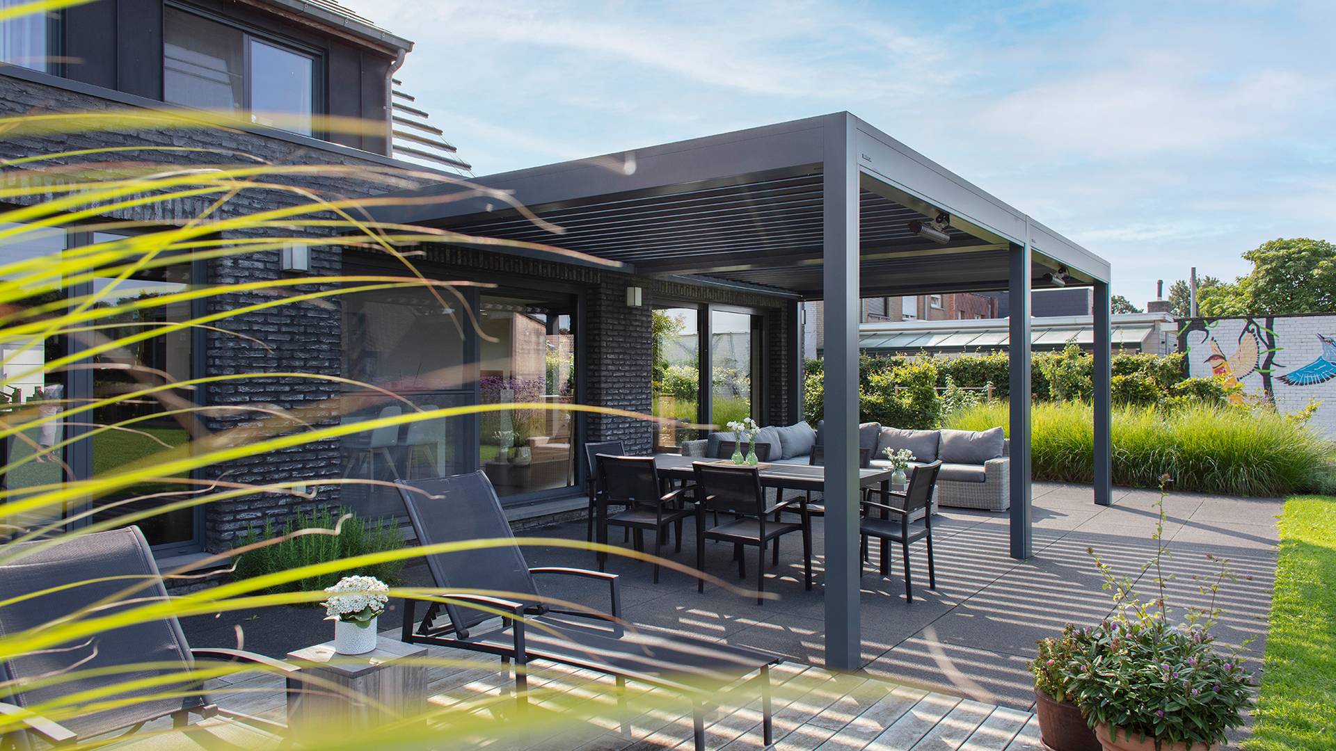 Pergola en aluminium à lames orientables installée sur une terrasse moderne, offrant de l’ombre à un espace repas extérieur.