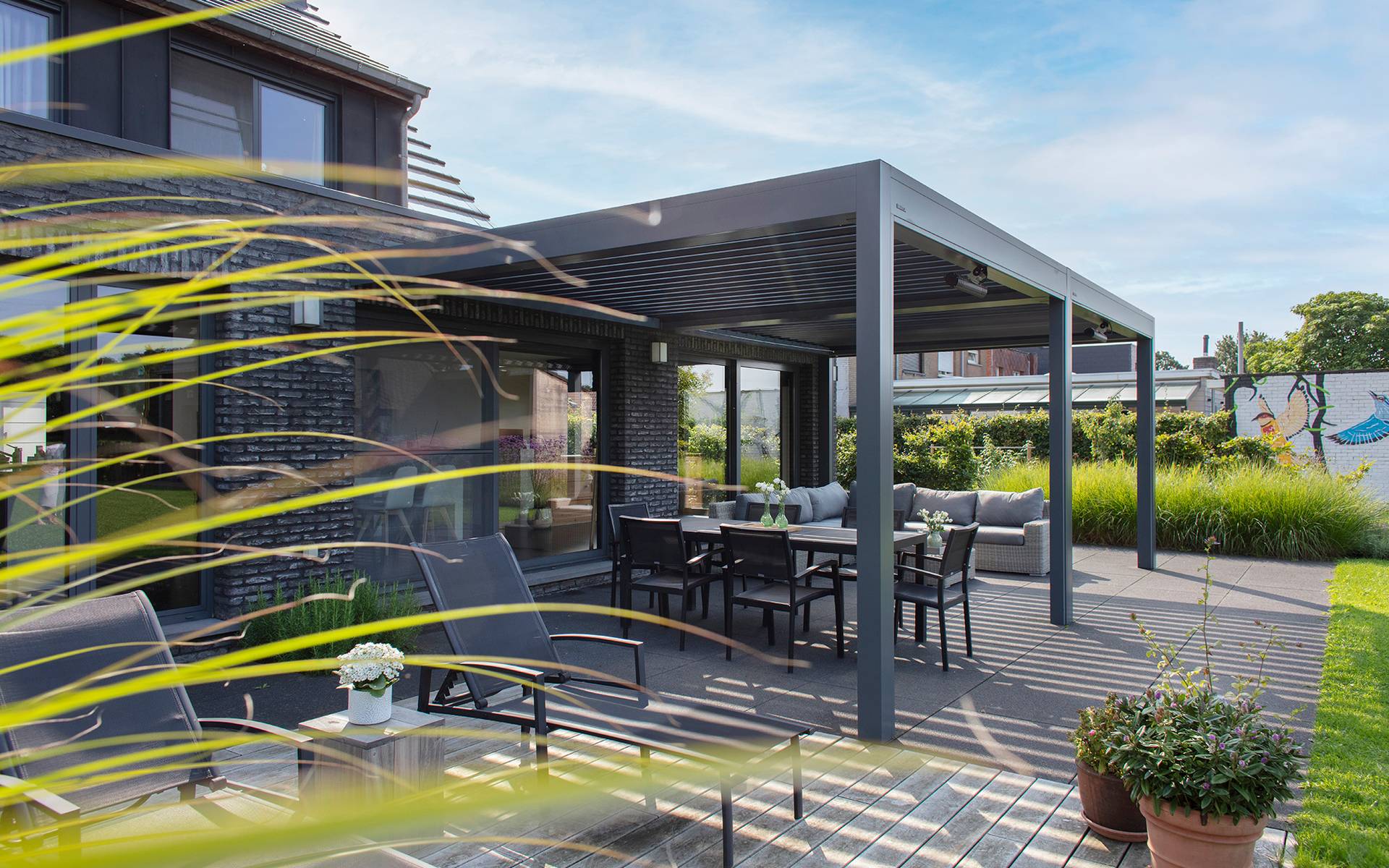 Pergola en aluminium à lames orientables installée sur une terrasse moderne, offrant de l’ombre à un espace repas extérieur.