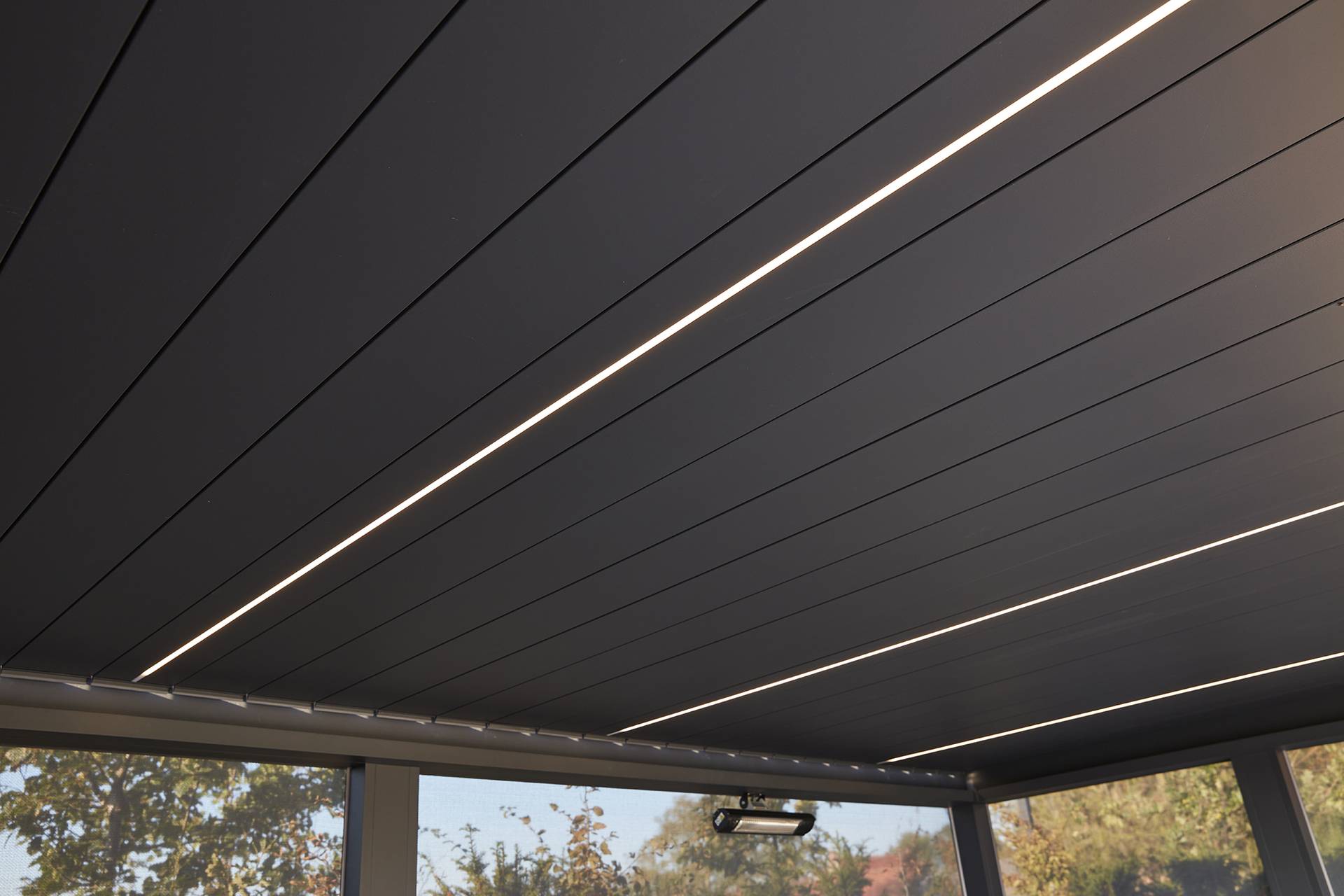 Nahaufnahme des Lamellendachs der Brustor B200(XL) Pergola mit integrierter LED‑Linienbeleuchtung, die das klare Aluminiumdesign und die stimmige Außenatmosphäre betont.