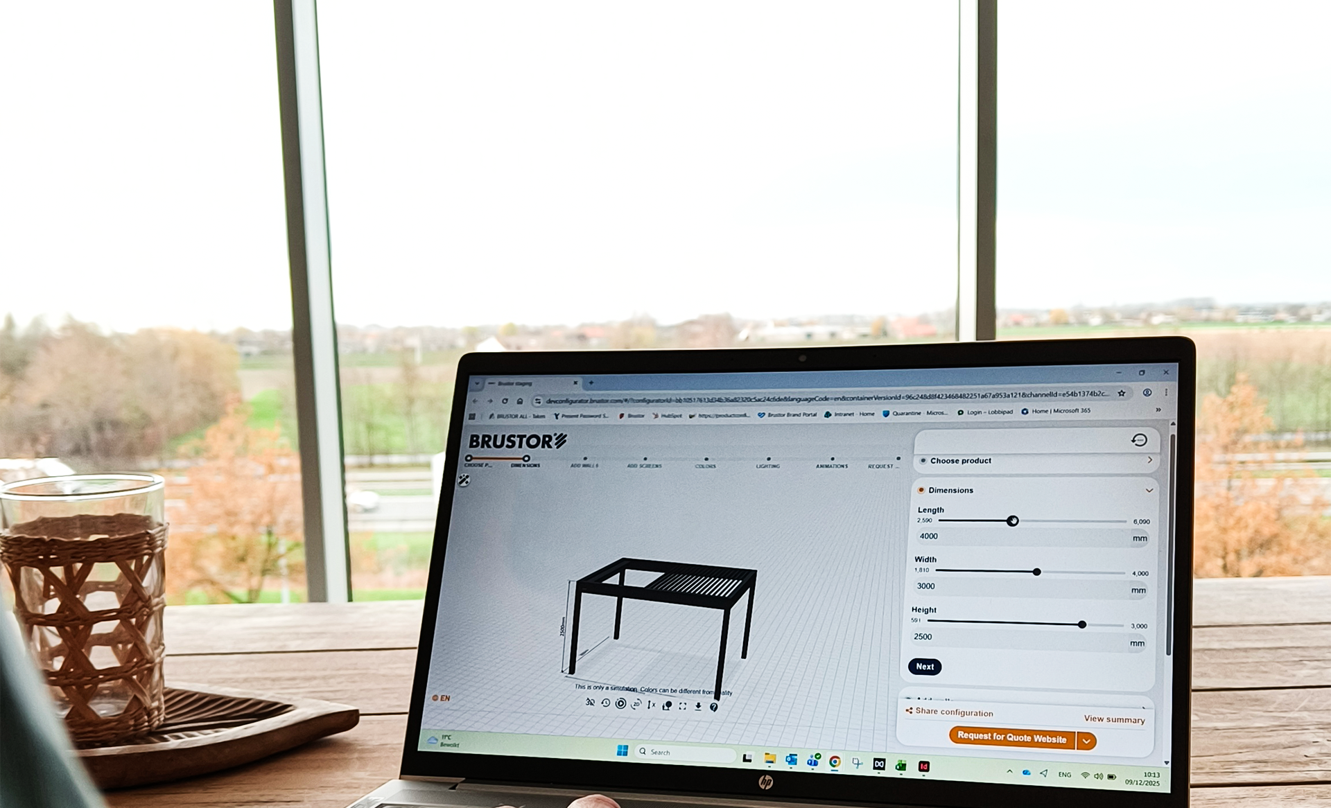 Personne utilisant un ordinateur portable pour configurer une pergola dans le simulateur 3D Brustor sur une table en bois avec vue extérieure.