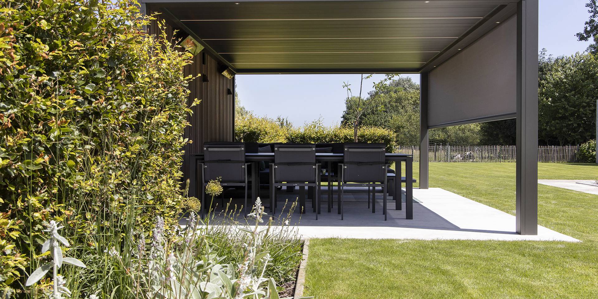 Pergola en aluminium avec ZIP‑screen intégré offrant un espace repas extérieur ombragé au bord du jardin.