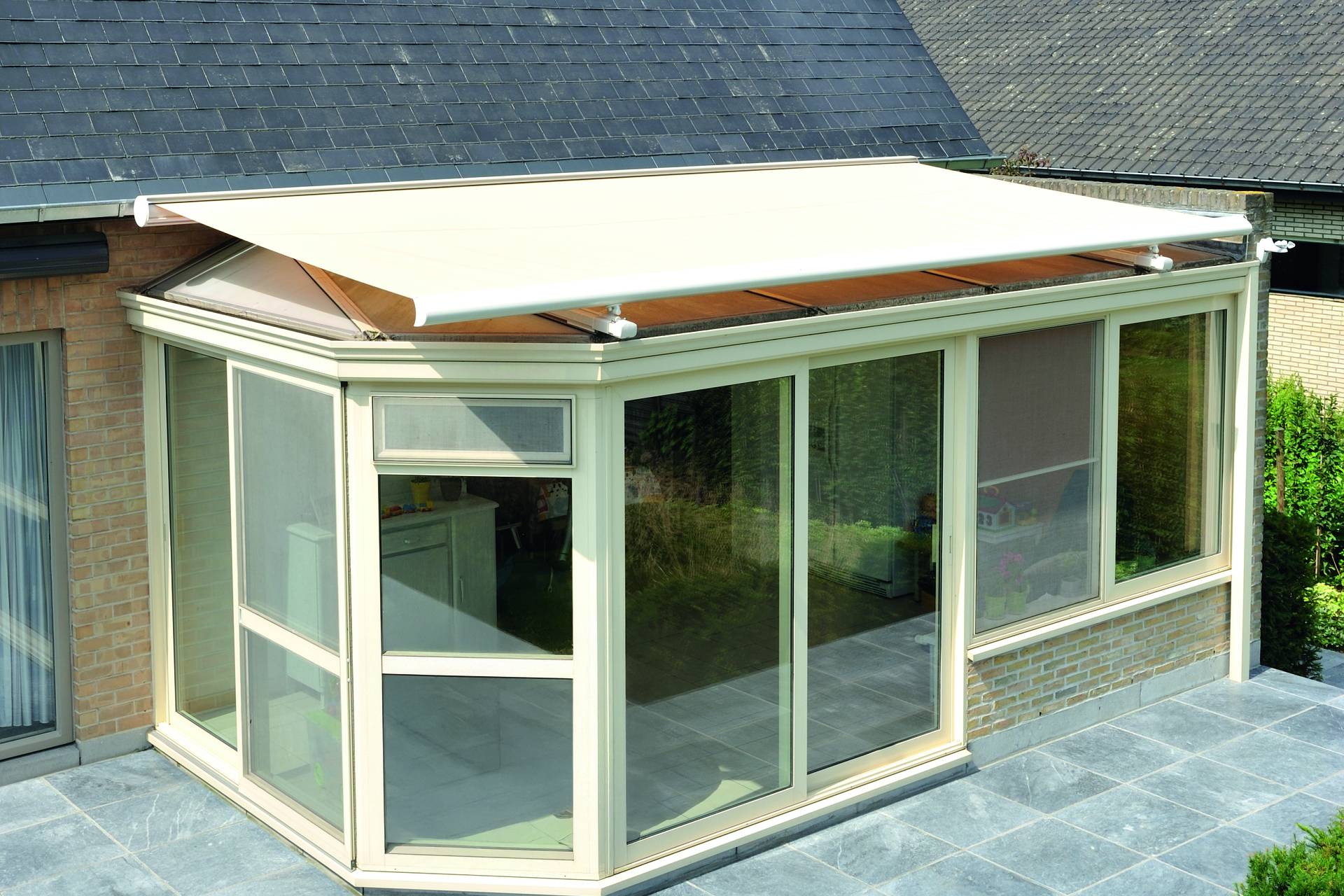 Brustor B127 conservatory awning mounted above an angled glass veranda roof providing tailored exterior sun protection for irregular roof shapes