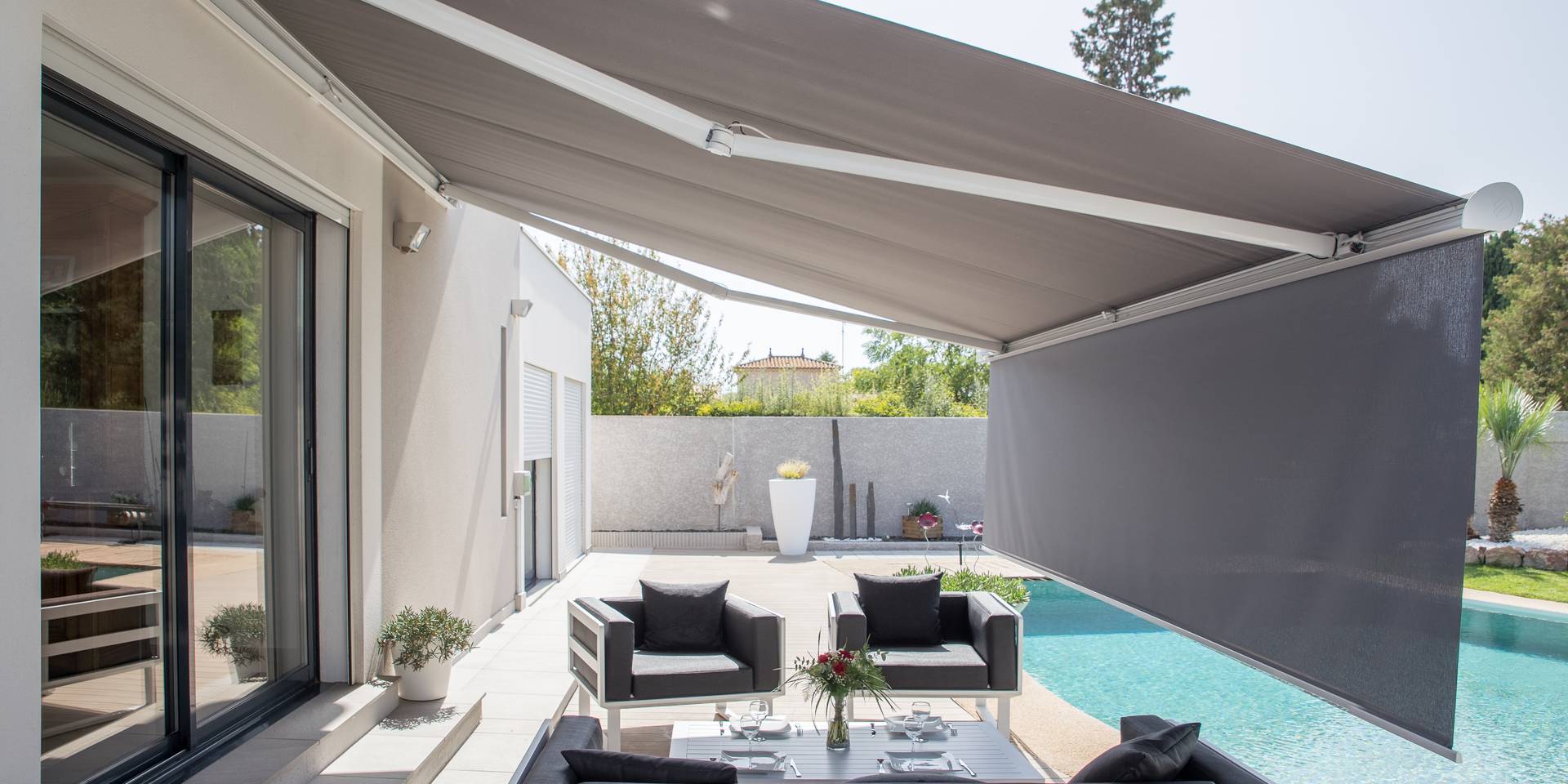 Aluminium awning with vertical drop‑down valance shading an outdoor lounge area beside a modern pool terrace.