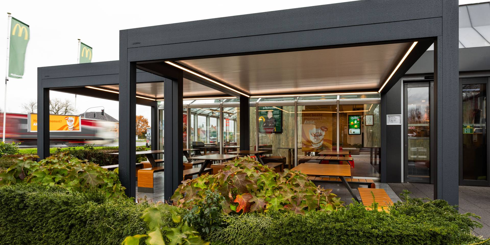 Aluminium fixed roof pergola with integrated LED lighting providing a sheltered outdoor seating area at a commercial location