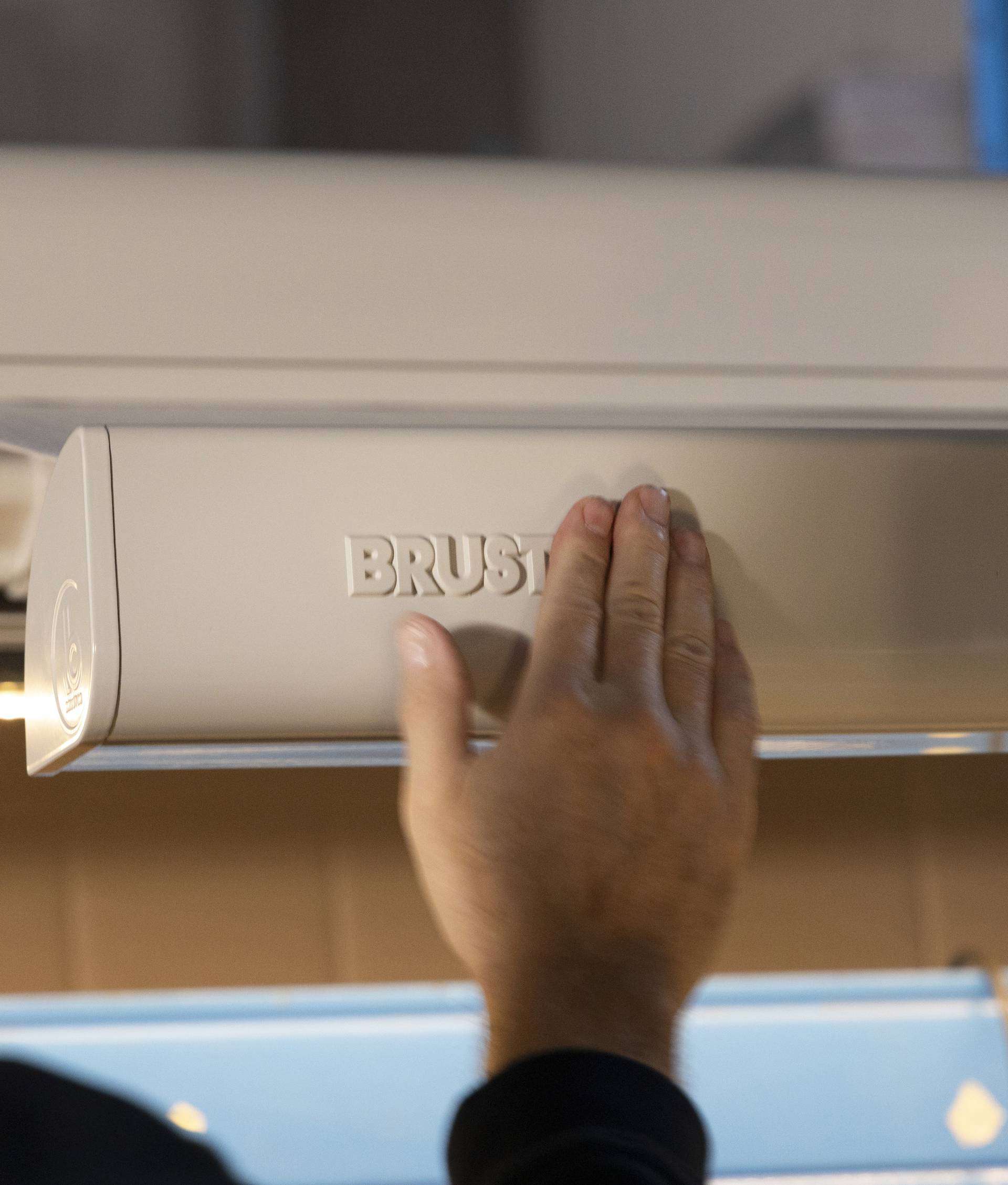 Hand die de cassette van een Brustor‑zonnescherm controleert tijdens de assemblage in de productieomgeving