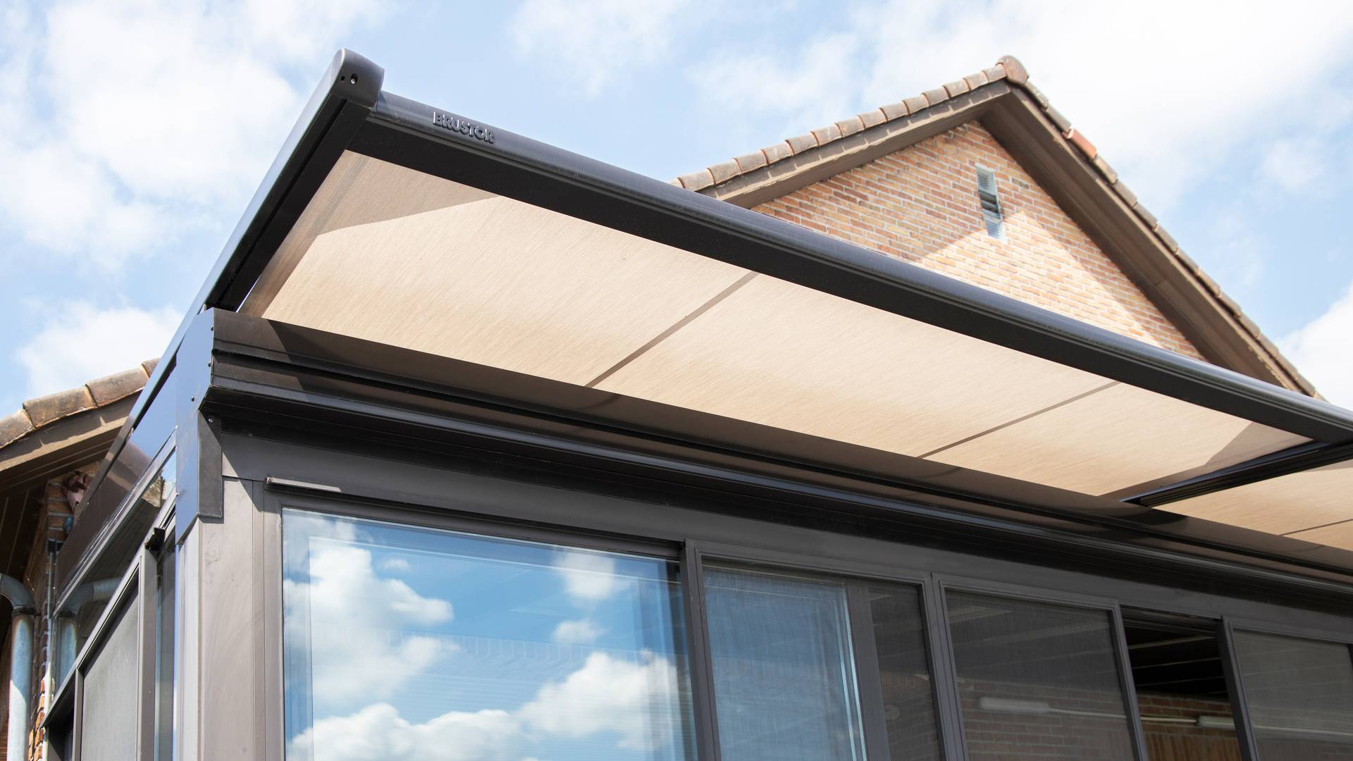 Toldo para veranda Brustor instalado sobre un techo de vidrio que proporciona protección solar exterior