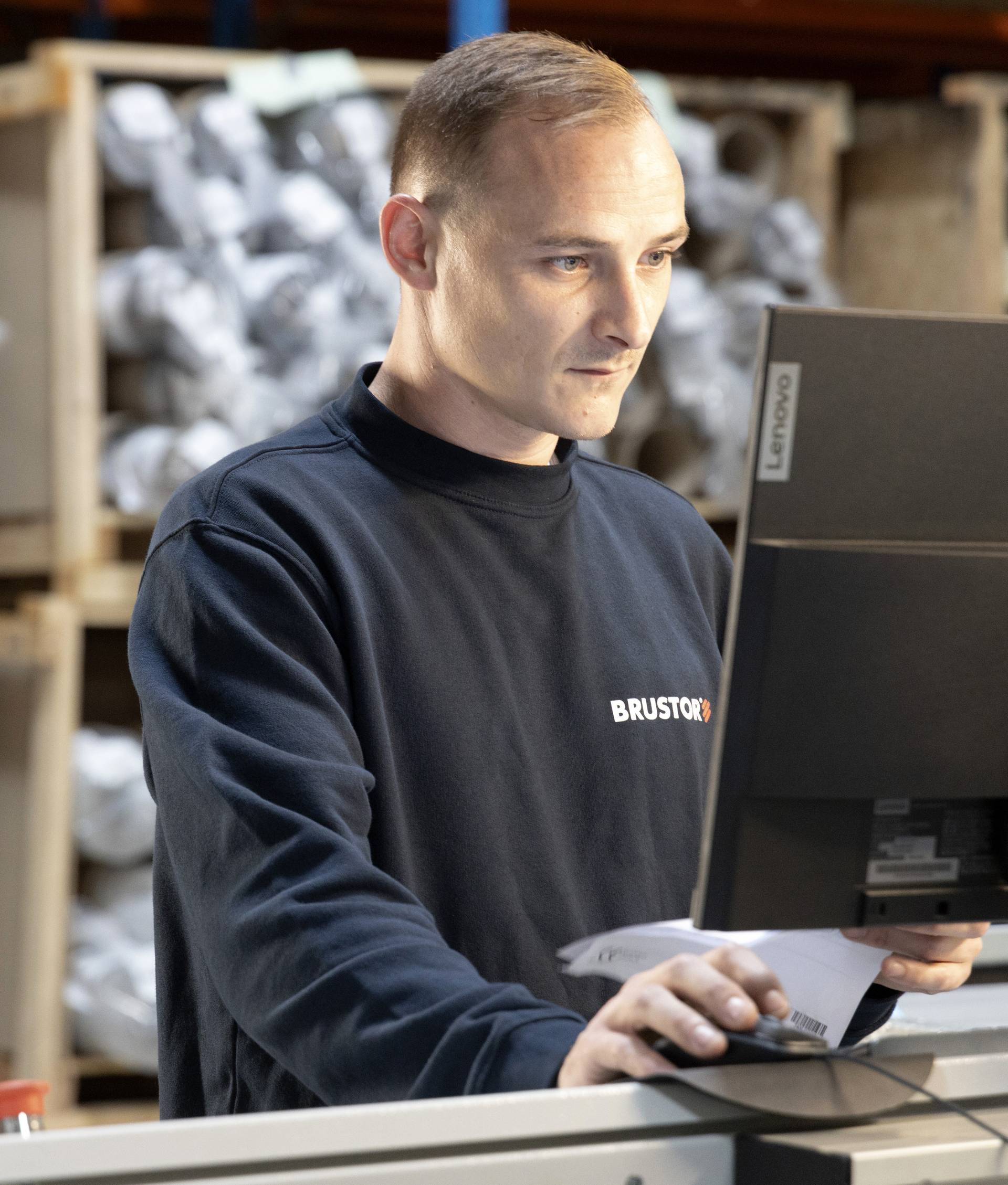 Brustor‑medewerker die aan een computergestuurde werkpost werkt in het magazijn.