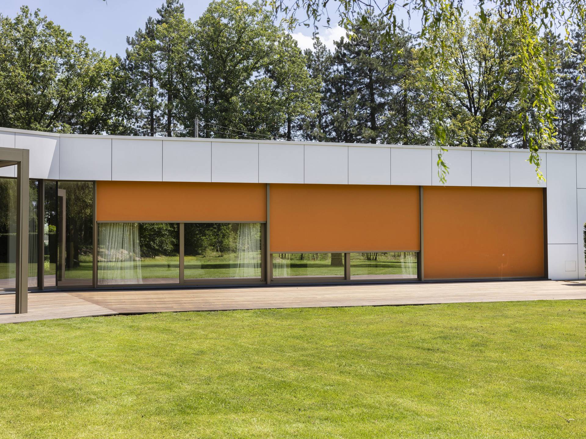 Villa moderne blanche avec de grands screens intégrés entièrement abaissés, illustrant la solution de protection solaire intégrée Brustor pour un confort et une intimité optimaux.