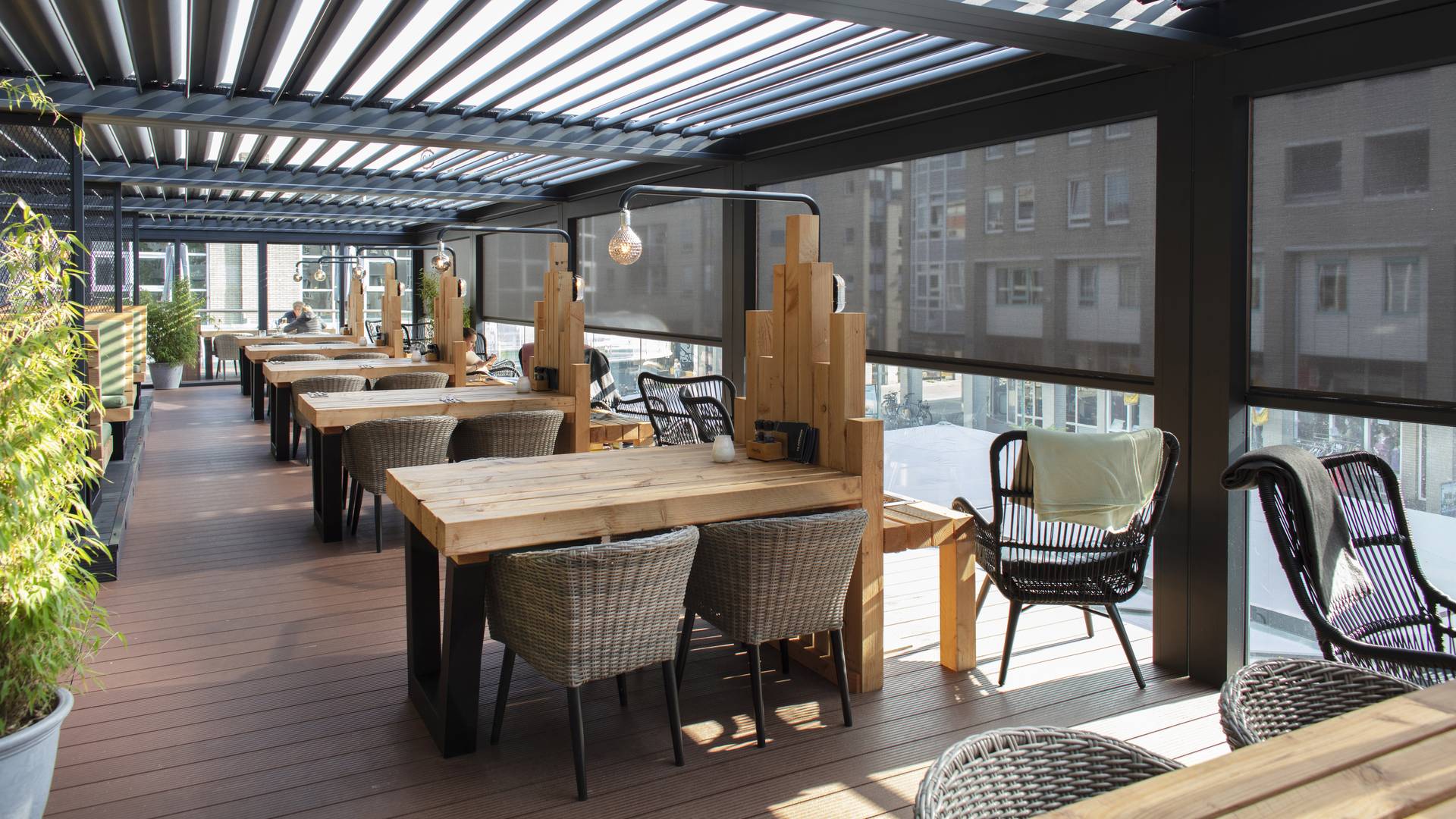 Terrassenüberdachung aus Aluminium mit Lamellen und ZIP‑Screens in dunkler Ausführung über modernem Außenbereich mit Sitzgelegenheiten