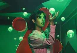 Eine Frau steht in einem futuristischen Raum und Lotto Kugeln schweben als Hologramme herum