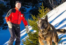 Ein Mitarbeirter der Österreichischen Bergrettung und ein Schäferhund im Schnee