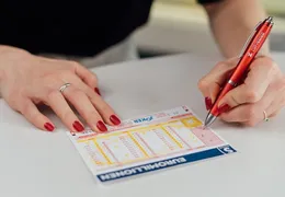 Jemand füllt einen EuroMillionen Wettschein aus.