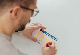 ein junger Mann füllt einen EuroMillionen Wettschein aus