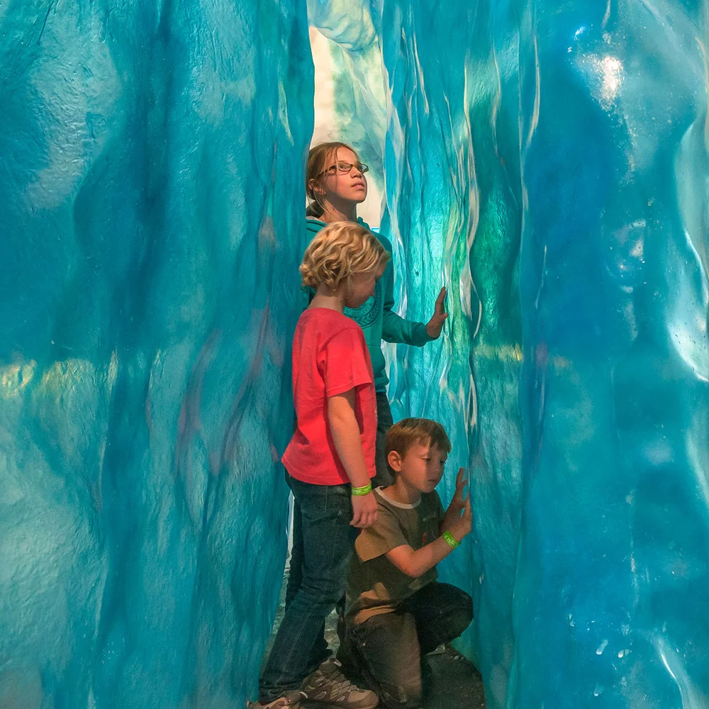 kids exploring an ice cave exhibit with glacier walls