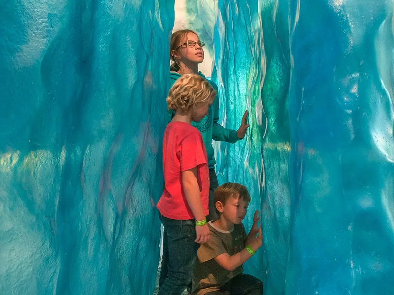 kids exploring an ice cave exhibit with glacier walls