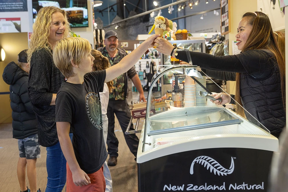 A boy receives an ice cream cone from a smiling staff at WIldlife Centre
