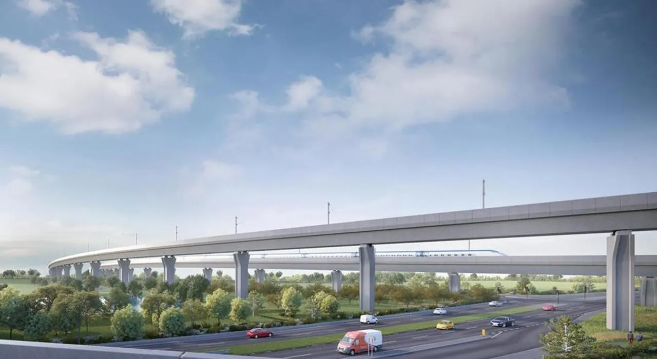 Concrete elevated rail viaduct with a high-speed train passing above a multi-lane highway, cars below and green fields under a blue sky.