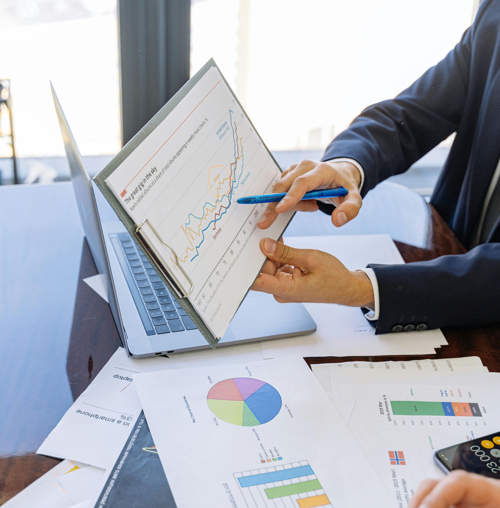 Consultant pointing at graphs on paper during a data strategy and business intelligence session, supporting AI-powered analytics, reporting, and data-driven decisions.