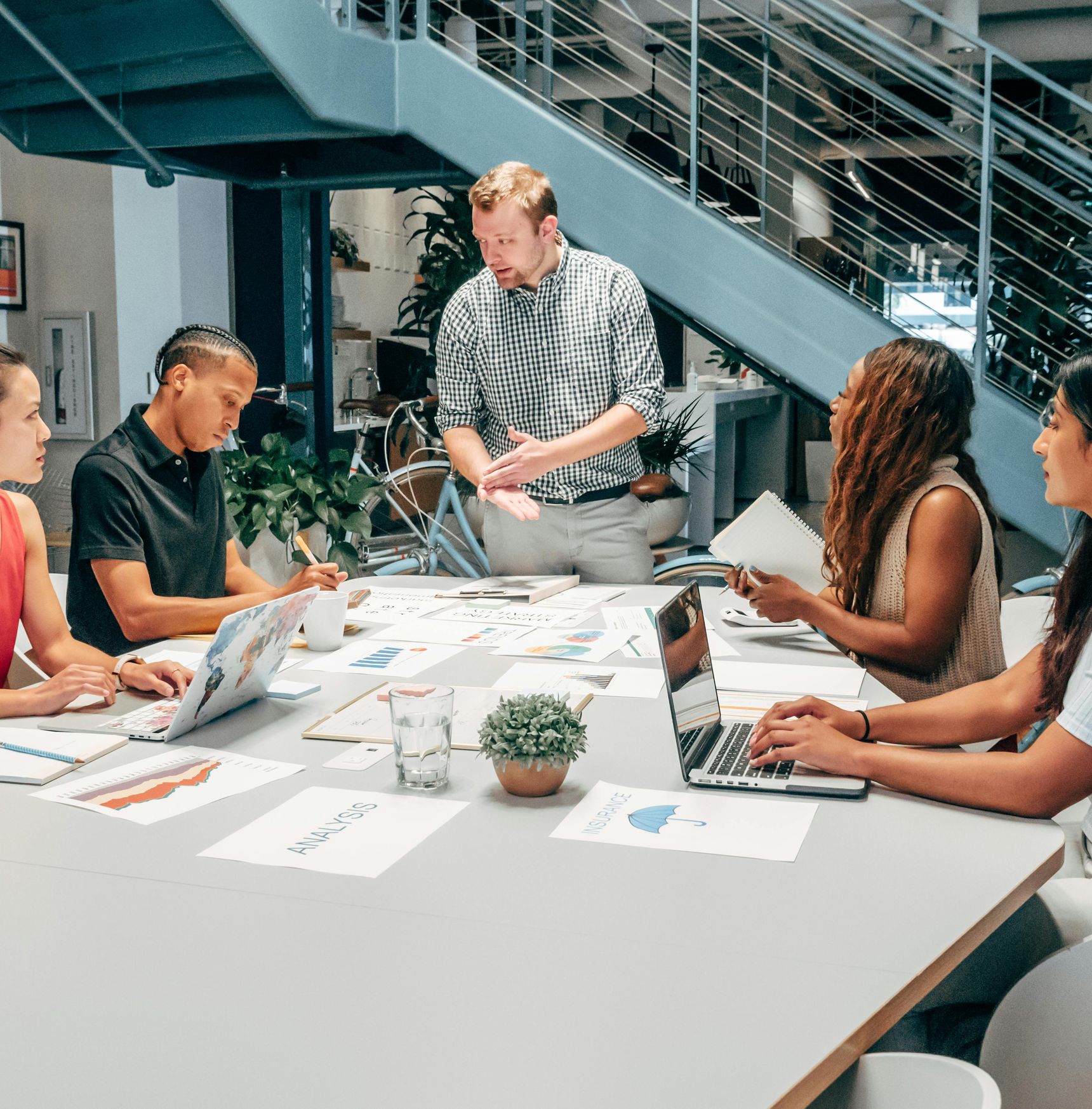 Team in a leadership development meeting with a leader presenting while others take notes, illustrating talent assessment and development, HR strategy consulting, and leadership skills.