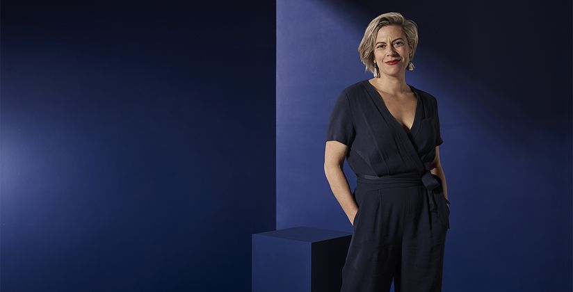 Dr Bridie O'Donnell standing against a dark blue backdrop