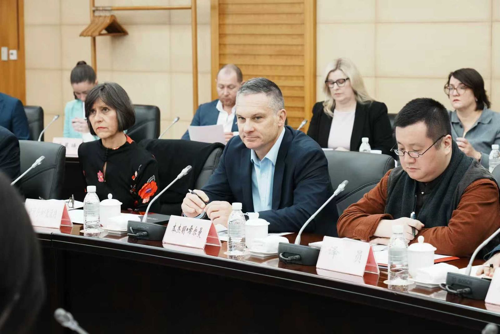 Australian delegates seated at a conference table with microphones and name cards during a meeting in China